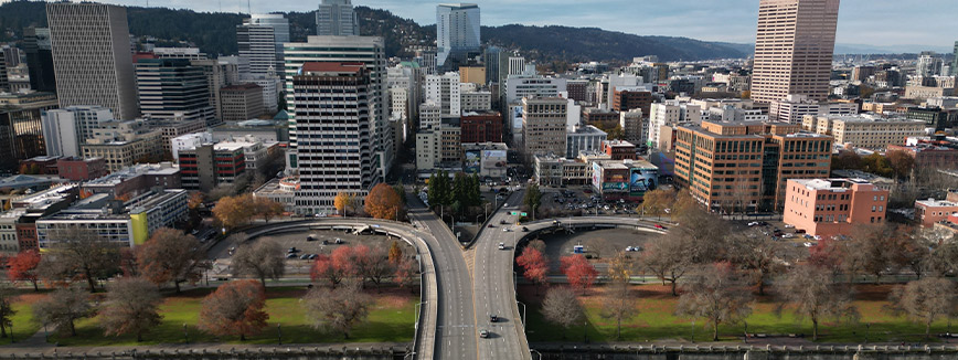 Morrison bridgehead in Portland Oregon. A bustling cityscape featuring skyscrapers and a bridge, representing the move to Portland and new beginnings in the Northwest.