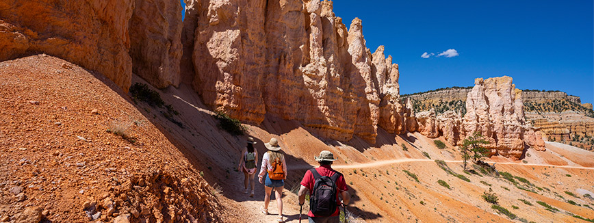 Hikers on a scenic trail leading to Bryce Canyon National Park, surrounded by stunning rock formations and natural beauty.