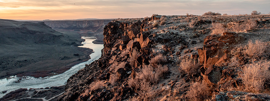 A picturesque sunset over a river and canyon, showcasing vibrant colors and serene natural beauty.