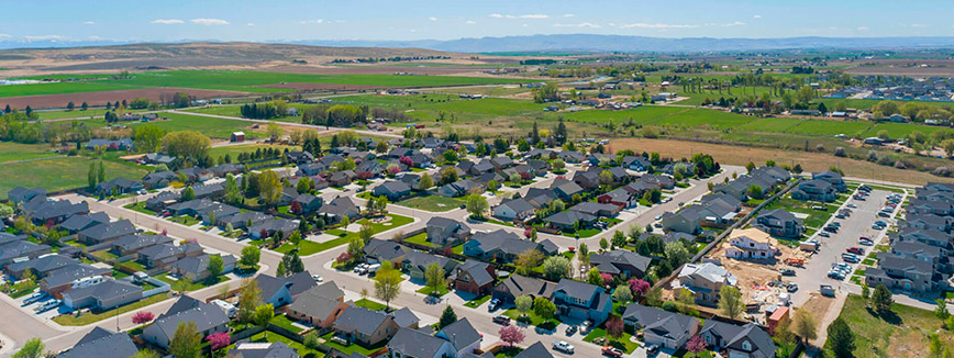 Overhead perspective of a Kuna neighborhood nestled in a valley, highlighting residential areas and surrounding landscape.