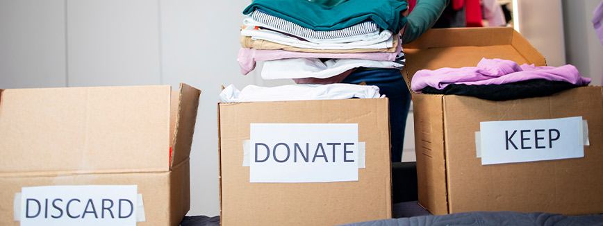 Image of a person placing clothes into a donation bin, promoting charity donations during the decluttering process.