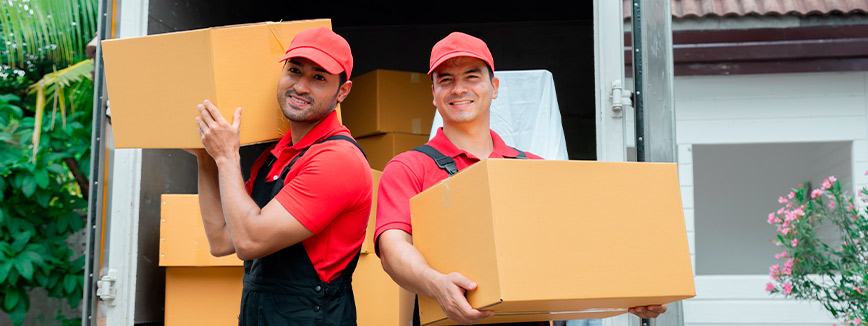 Two men dressed in red shirts load boxes into a moving truck, showcasing a step in the pre-move decluttering plan.